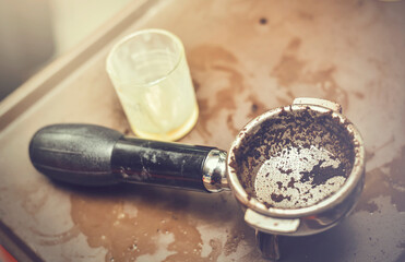 In selective focus of old hot coffee grain with wet and dirty portafilter.Close up of professional barista concept
