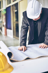 Image of engineer checking blue print.Young architect man or engineer working on his plane project at site construction work