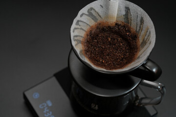 Hand driper of Prepare drip coffee on digital scale in Studio dark tone.