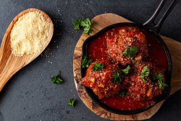 Close up view of three traditional large Italian meatballs in sizzling tomato sauce in cast iron...