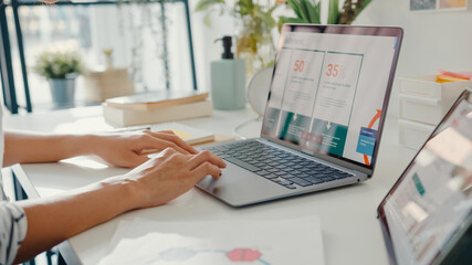 Close-up young asia lady freelance focus on work finance graph account chart market plan in laptop for remote meeting with company at home. Girl student learn online at house, Work from home concept.