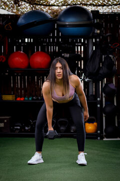 mujer latina haciendo ejercicio con pesas en gimnasio al aire libre.  Entrenador personal con cuerpo atlético Photos