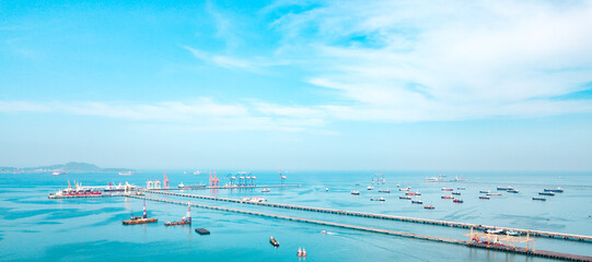 Aerial view from drone, pier to the crane bridge is unloading container cargo to large vessel in...