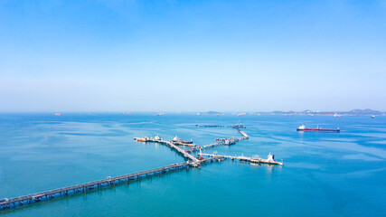 Fototapeta na wymiar Aerial view from drone, Oil pipes to oil tanker ships at pier off the coast in beautiful peaceful environment. Professional business logistics and transportation of energy fuels.