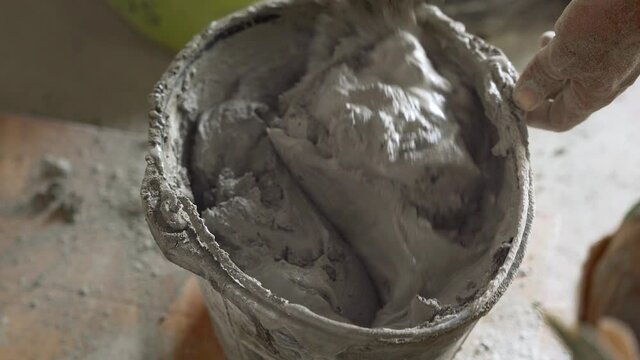 Hand mixes mortar in bucket. Handheld