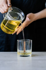 The girl pours wax into glass glasses with wicks.