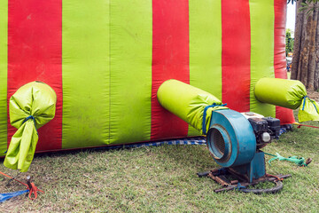 The old portable air blower pump fan install with green and red inflatable bouncer ball house...