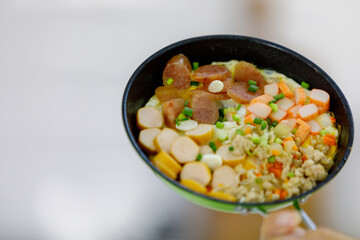 Tasty healthy food of hotdog, hams, crab stick on green flying pan shown by mom on orange apron that learned to cook for kid and family at home kitchen