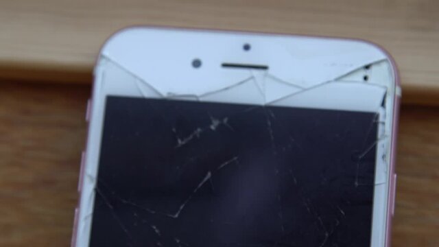 Dolly Forward Coming Into Focus On A Smashed White and Pink Smartphone Rested Upwards