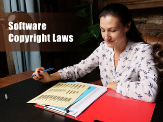 Fototapeta premium Legal concept about Software Copyright Laws Female office workers with yellow shirt holding and writing documents on office desk