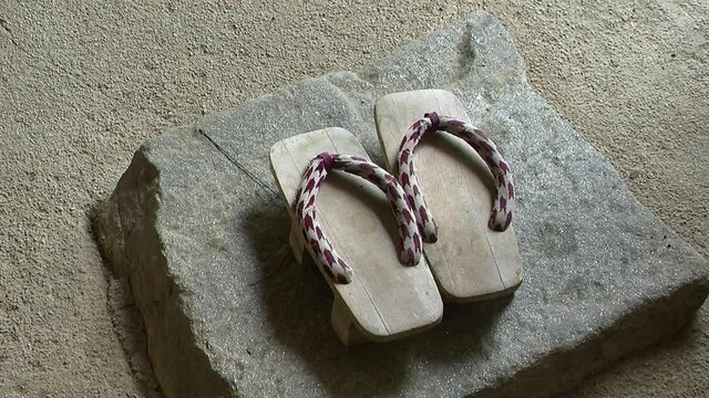Japanese geta sandals rest on a stone in a Japanese house.