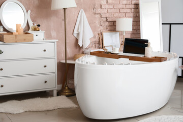 Stylish interior of modern bathroom with laptop and burning candles