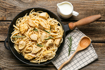 Frying pan with cooked chicken and pasta on table