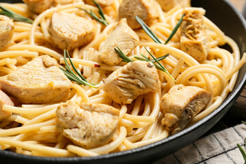 Frying pan with cooked chicken and pasta on table, closeup