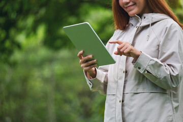 Fototapeta premium Closeup image of a woman holding and using digital tablet in the outdoors
