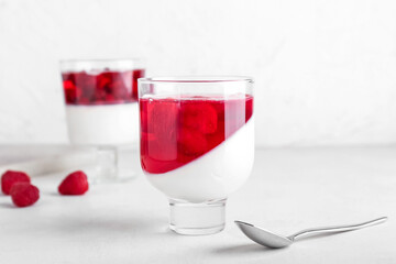 Glass of tasty raspberry jelly on light background