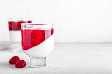 Glass of tasty raspberry jelly on light background
