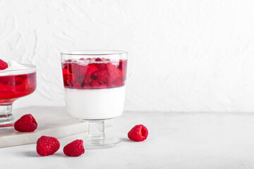 Glass of tasty cranberry jelly on light background
