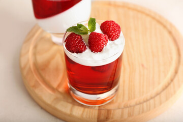 Glass of tasty raspberry jelly on light background