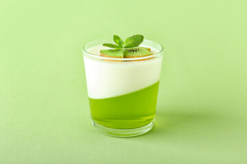 Glass of tasty jelly with kiwi on color background