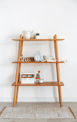 Shelf with alarm clock and decor near light wall