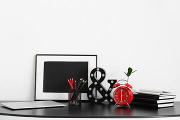 Alarm clock and decor on table near light wall