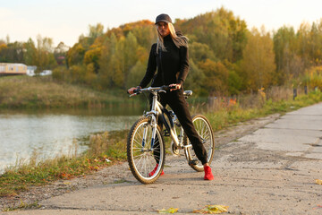 beautiful sports woman in trendy sports jumpsuit posing near a bike in nature