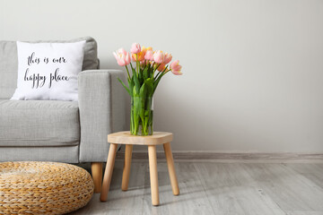 Bouquet of tulip flowers on table near light wall in room