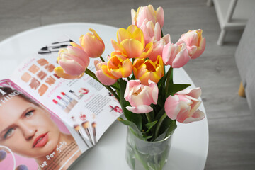 Bouquet of tulip flowers and magazine on table in room