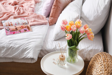 Tulip flowers and reed diffuser on table in bedroom