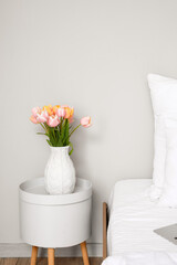 Tulip flowers on bedside table near white wall in room