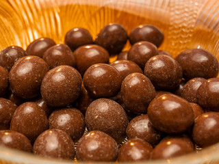 Peanuts in chocolate with a sugary surface in a glass bowl - selective focus