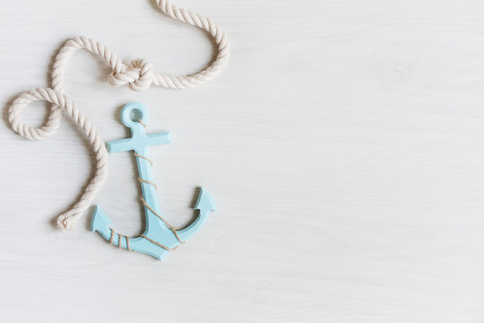 Sea background with anchor and marine rope on white wooden deck top view.