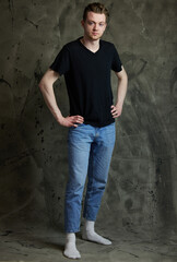 Horizontal portrait of a stylish caucasian guy in full growth on a gray background
