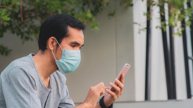 Man wear surgical mask protect covid19 and using smartphone outdoor