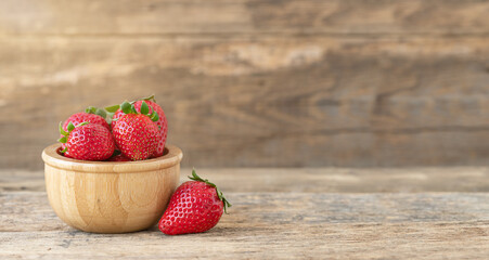 Summer background with strawberrires in the bowl on wooden backdrop