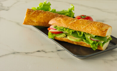 whole grain long baguette vegan sandwich with lettuce, avocado, tomato and cheese. Healthy snack and food to go