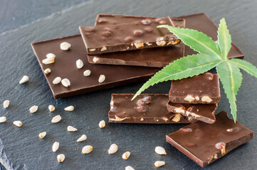 Marijuana leaves and dark chocolate on black background