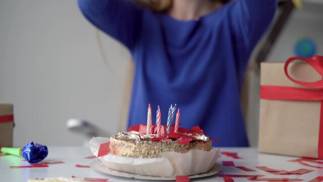 close-up of a birthday cake with unlit candles stands on the table. The woman throws confetti at him. The concept of fireworks at home in honor of birthday.