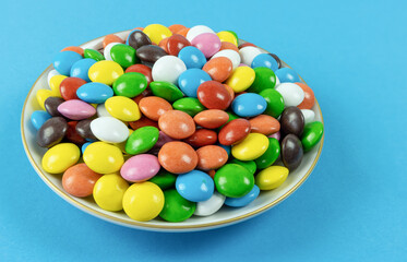 Round milk chocolate balls on a plate on a blue background
