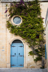 Fototapeta na wymiar Ivy growing over the blue doorway of a monastery in Mdina, Malta