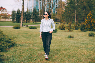 Photo of young business woman walking in park during free time