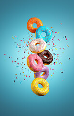 Colorful donuts flying with sprinkle explosion on blue background.