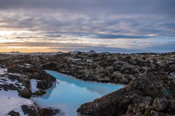 Unique landscape with lava fields and blue thermal water in Iceland. Outside Blue Lagoon in Iceland. The blue water between the lava stones. Hot springs Blue Lagoon in Iceland.