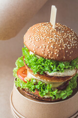 Vegan burger with vegetables and hummus, brown kraft background. Recycling food packaging, zero waste concept.