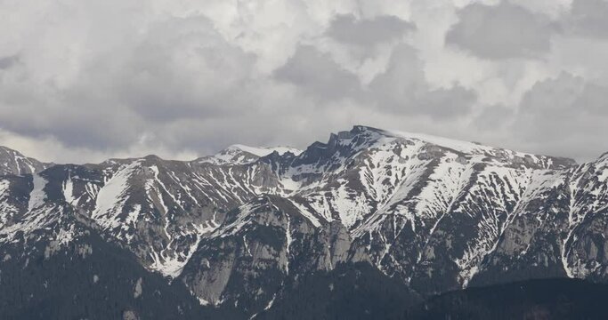 Heavy clouds over the Bucegi mountains in Romania during a spring day, as seen from the hills of Pestera village.