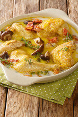 Alsace Coq au vin Riesling chicken in white wine with cream and mushrooms close-up in a saucepan on the table. Vertical