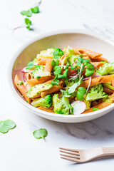 Lentil pasta with broccoli, avocado, radish and sprouts in white bowl. Healthy vegan recipe concept.