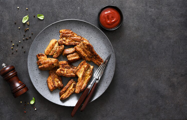 Grilled ribs in a large plate on a stone black table. Picnic. BBQ. View from above.