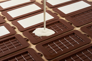 melted white chocolate with hazelnuts poured into a mold on a wooden table.